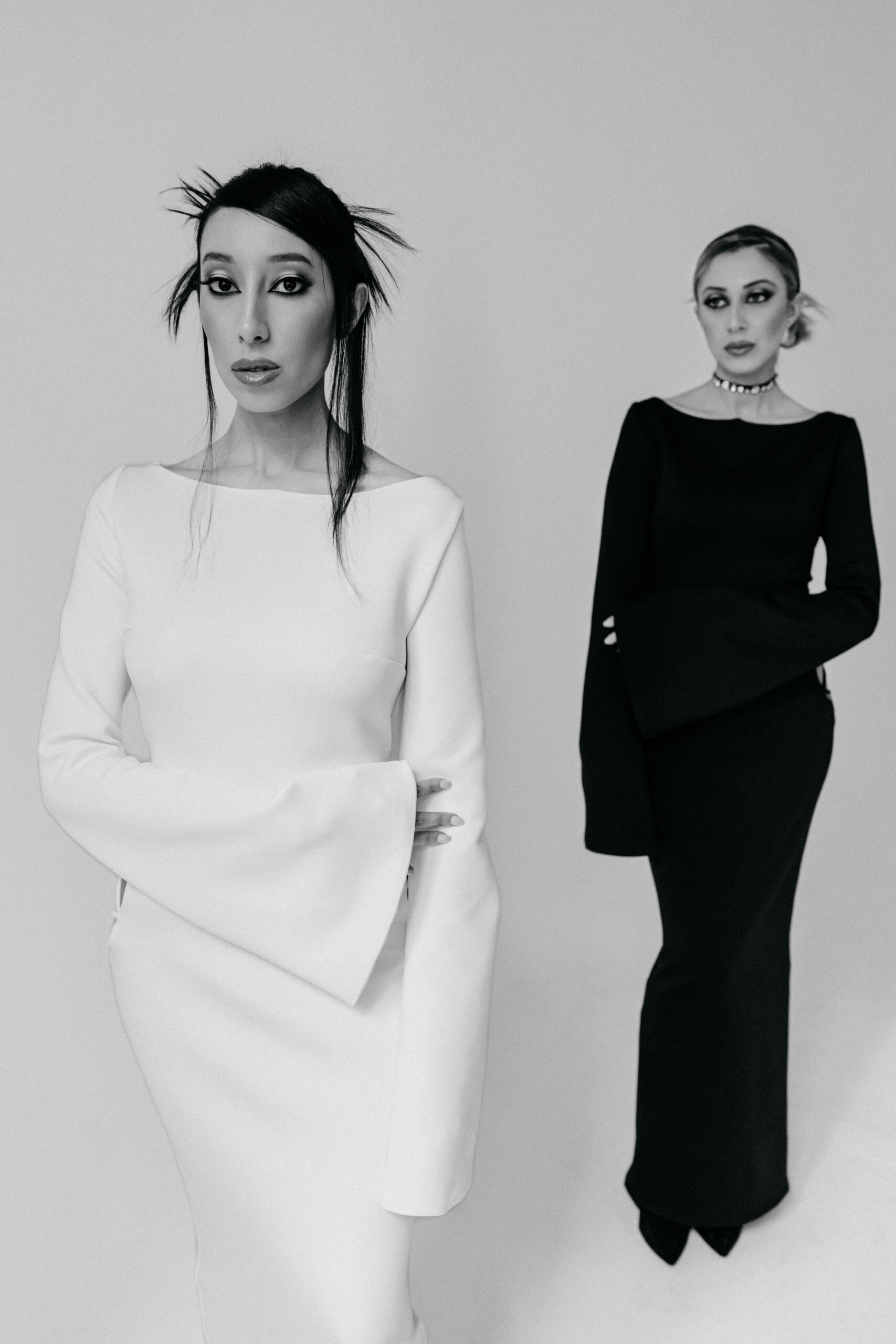 Due modelle indossano abiti LegameBrand in bianco e nero, una con l'abito nero guarda l'altra con l'abito bianco, creando un'immagine di eleganza classica e contrastante